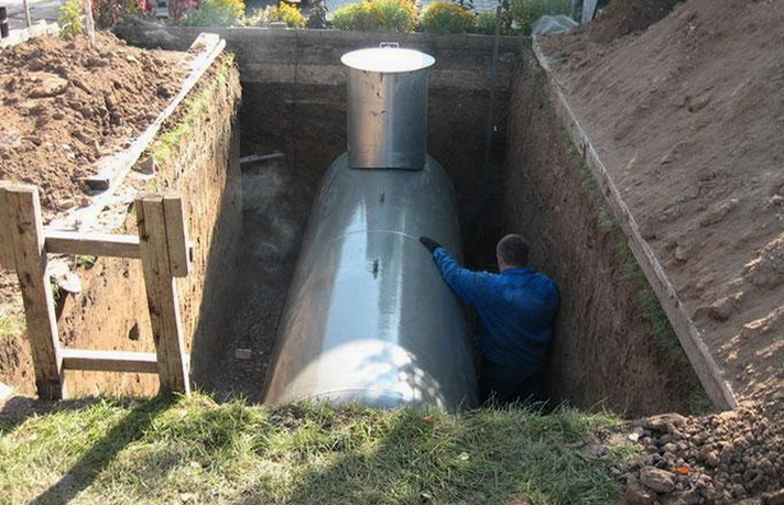 Человек монтирует газгольдер в траншее